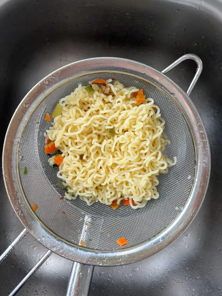 Rinsing cooked noodles under cold running water for cold ramyeon