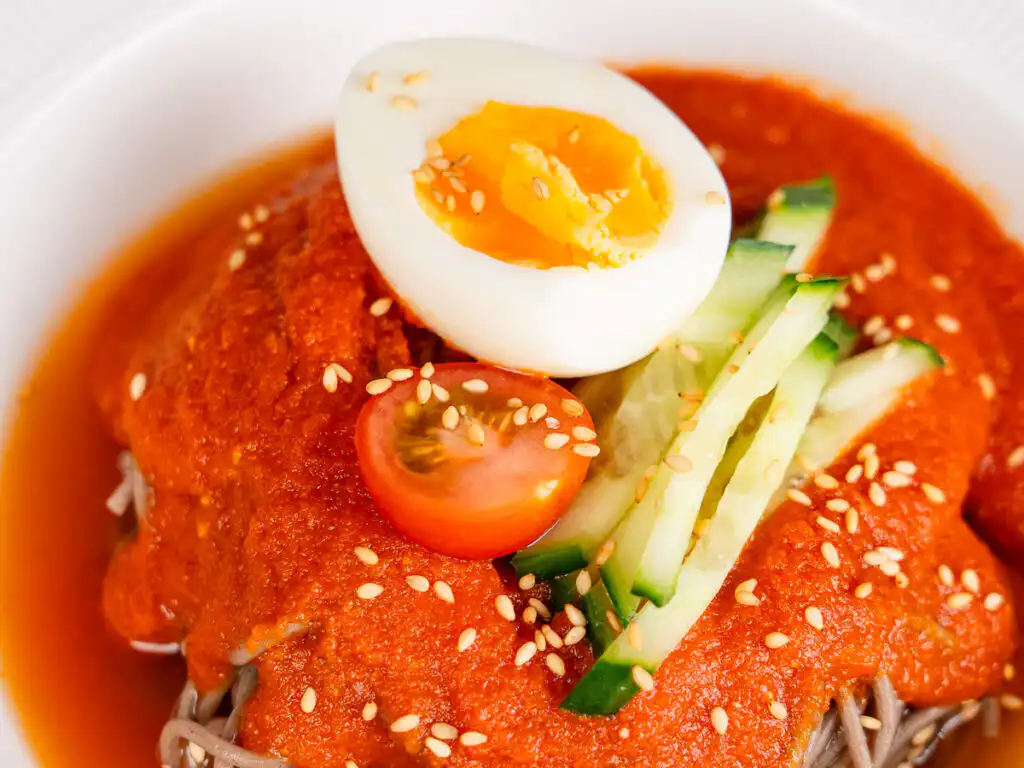 Tomato Gochujang Bibim Guksu - Summer Spicy Cold Noodles close up of gochujang bibim guksu toppings with sesame seeds