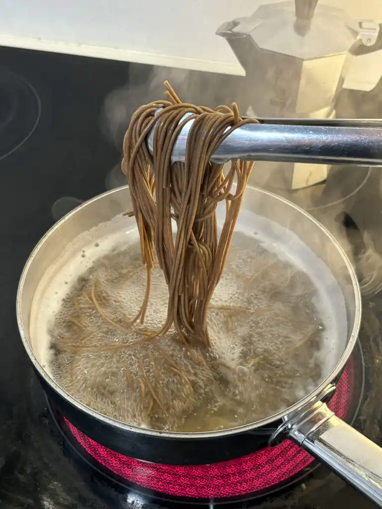 Tomato Gochujang Bibim Guksu - Summer Spicy Cold Noodles cooking buckwheat noodles in a pot of boiling water