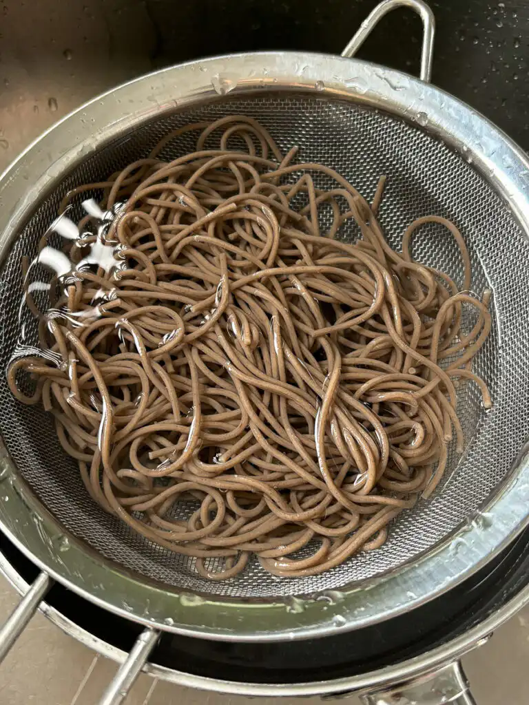 Tomato Gochujang Bibim Guksu - Summer Spicy Cold Noodles rinsing cooked buckwheat noodles under cold running water