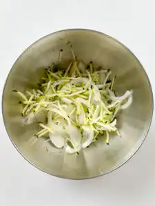 Sliced onion added to salted zucchini
