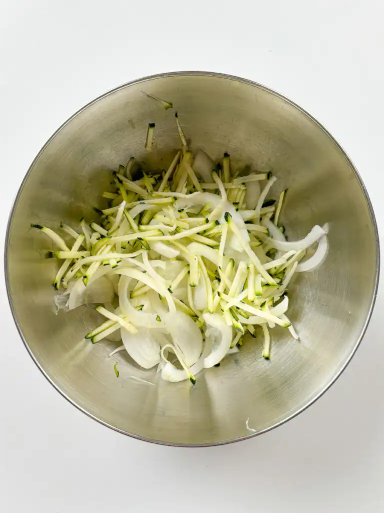 Sliced onion added to salted zucchini