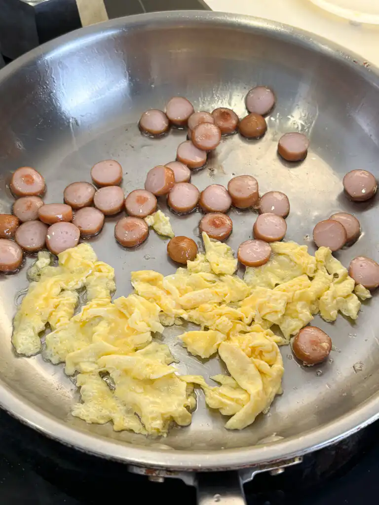 Buldak Fried Rice: Stress Blowing Buldak Sauce Rice in 10min Egg being scrambled next to fried sausage in a pan for budak sauce rice