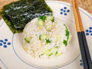 A meal prep bowl containing Korean seaweed rice mixed with sea salt, sesame oil, and diced raw cucumber.