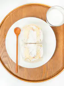 Fresh peach sando sliced cleanly in half on a breakfast table setting.
