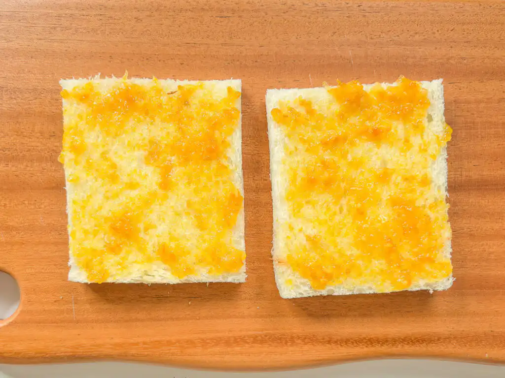 Earl Grey Peach Sando: Korean Cafe Fruit Sandwich Spreading orange marmalade jam onto two slices of white sandwich bread.