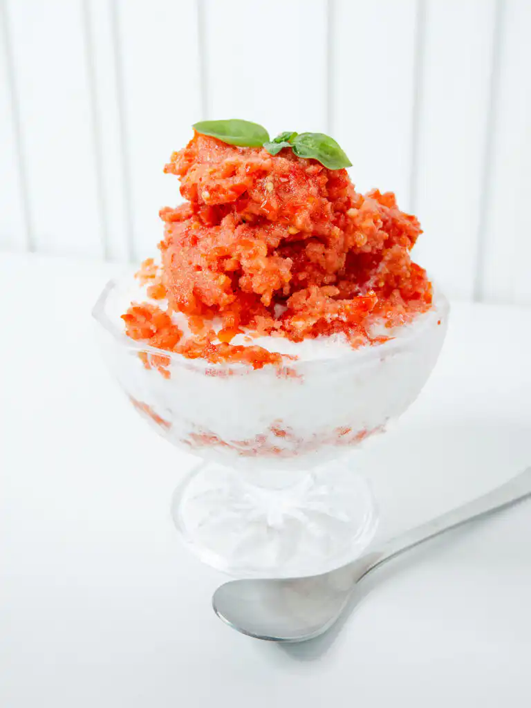 Fluffy white yogurt ice peeking through layers of red tomato bingsu purée.