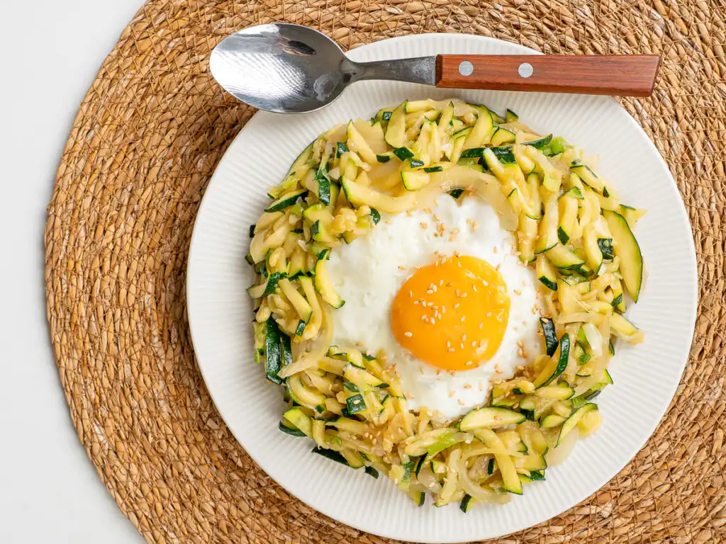 Korean Zucchini Rice Bowl: Easy Aehobak Deopbap Recipe Aehobak deopbap served alongside traditional Korean side dishes on a wooden table.