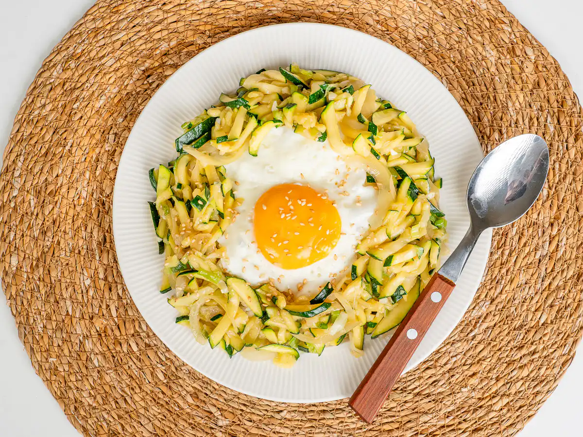 Korean Zucchini Rice Bowl: Easy Aehobak Deopbap Recipe Overhead view of an easy zucchini rice bowl featuring a golden egg yolk and sesame garnish.