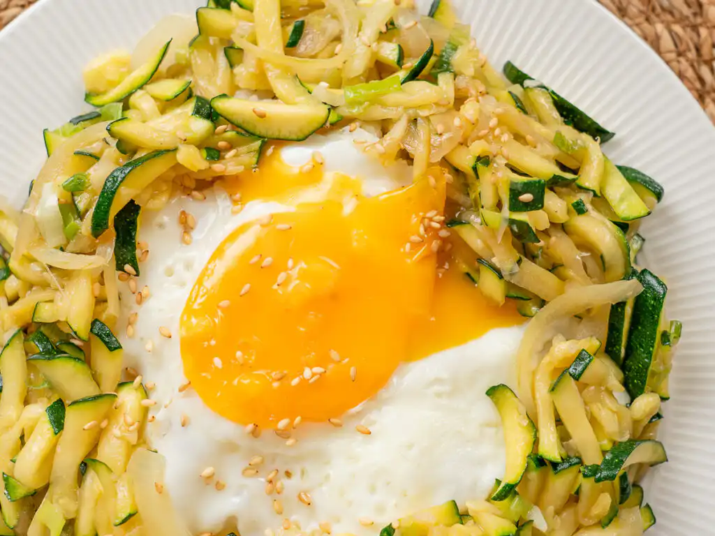 Easy zucchini rice bowl garnished with toasted sesame seeds and chopped green onions.