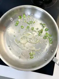Korean Zucchini Rice Bowl: Easy Aehobak Deopbap Recipe Adding sliced white onions to the pan with sautéed green onions and garlic.