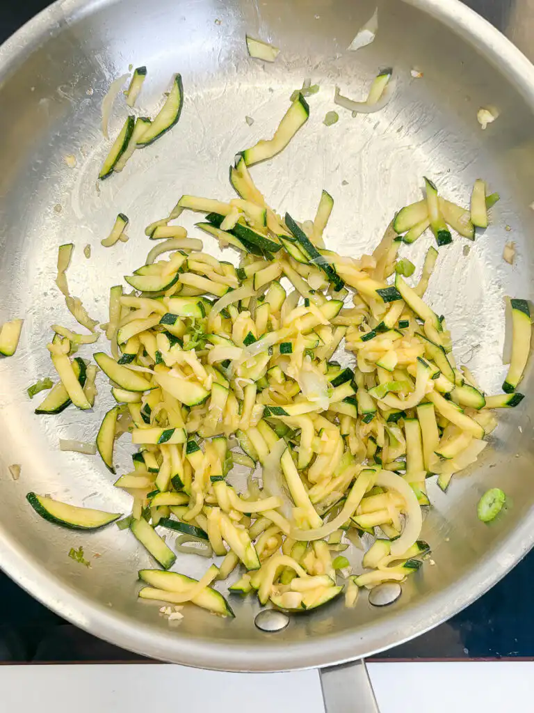 Korean Zucchini Rice Bowl: Easy Aehobak Deopbap Recipe Stir-frying zucchini slices in a pan until cooked through and glossy.
