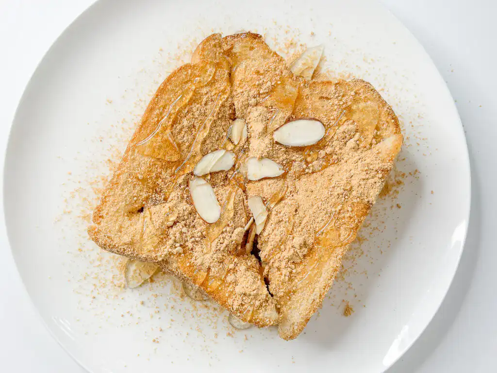 Sliced almond pieces sprinkled over dusting of konggaru on top of injeolmi toast.