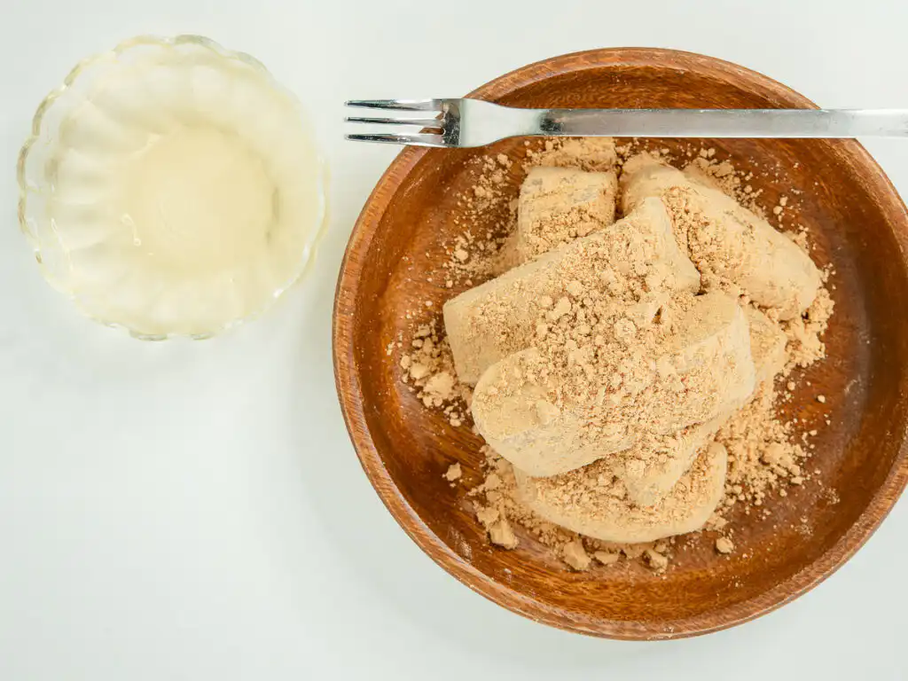 5 Min Microwave Injeolmi: Quick Korean Sweet Rice Cake Bite-sized microwave injeolmi coated in roasted soybean powder on a wooden plate.