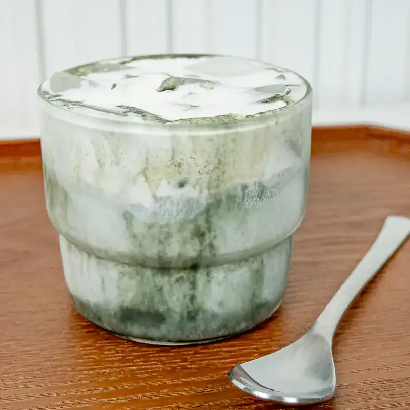 Korean Mugwort Latte: Easy Caffeine-Free Cream Ssuk Latte Front view of a Mugwort Cream Latte in a glass, with milk at the bottom and a mugwort gradient and cream foam layered above