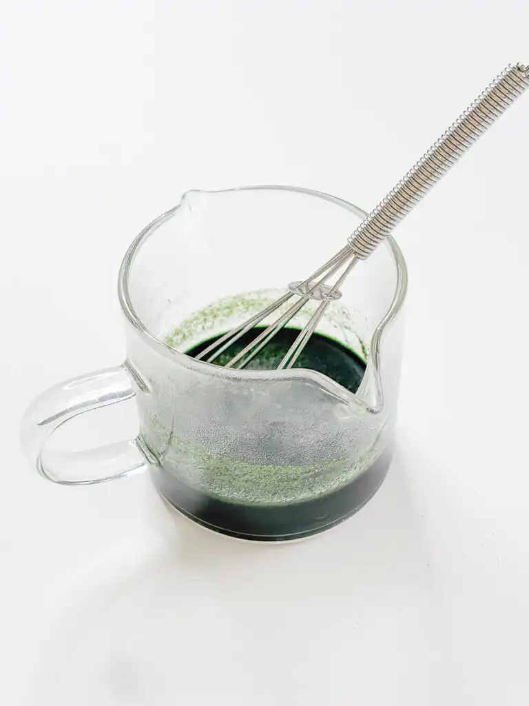 Mugwort powder dissolved in hot water into a deep green liquid, the base for Mugwort Cream Latte