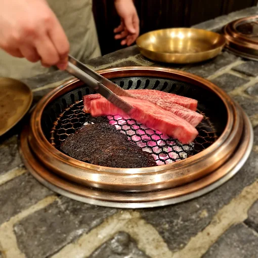 Justin Bieber Seoul Hotspots: 10 Places He Visited in Korea Hanwoo slices grilling over charcoal at SNY, one of Justin Bieber’s Seoul hotspots